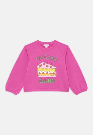 Pink sweatshirt with raglan sleeves, featuring a graphic of a cake and the text "THE CAKE GANG" in green, with a soft texture.
