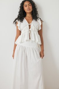 Witte twee-delige outfit met een ruffled top met korte mouwen en een strik aan de voorkant, en een lange, geraffineerde rok met een elastische tailleband.