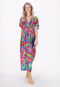 Rochie maxi colorată, cu un model în culori vibrante, incluzând forme îndrăznețe în roșu, verde, albastru și mov. Fabrică moale, cu un design tip wrap și legătură pe lateral.