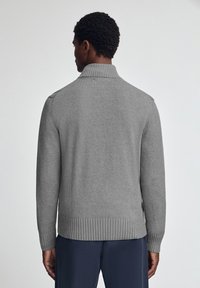 Maglione grigio lavorato a maglia con colletto alto e fondo a coste. Presenta una texture liscia e maniche lunghe con dettagli sulle spalle.