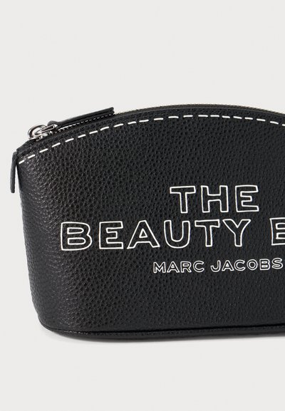 Must must beebus tapidaga mustambalit, kõver ülaosa, valge õmblus ja julged trükitud tekstid: "ILU E" ja "MARC JACOBS."