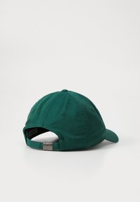 Green cotton cap with a curved brim, adjustable metal clasp, and ventilation eyelets, featuring a solid color with a matte finish.