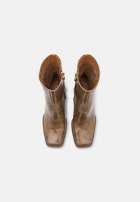 Bruine leren enkelboots met een glanzende afwerking, vierkante teen en zijritsen. Interieur gevoerd met zacht materiaal, met een slanke silhouet.