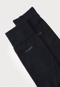 Calcetines azul marino oscuros con puños acanalados, que presentan una textura suave y un sutil logo "BOSS" en gris cerca del tobillo.