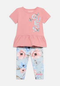 Ροζ κοντομάνικη μπλούζα με πεπλούμ περιθώριο, που διαθέτει ασημένια γράμματα και γραφικά με πεταλούδες. Ανοιχτό μπλε κολάν με λουλουδάτα και πεταλουδένια σχέδια.