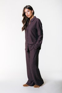 Completo a due pezzi in velluto a coste di colore viola scuro, composto da una camicia con bottoni e pantaloni a gamba larga, caratterizzato da un motivo testurizzato e una vestibilità rilassata.