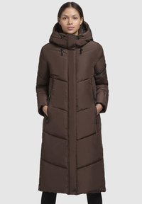 Geacă puf maro cu un design lung, guler înalt, glugă și buzunare cu fermoar. Prezintă modele quilted orizontale și verticale.