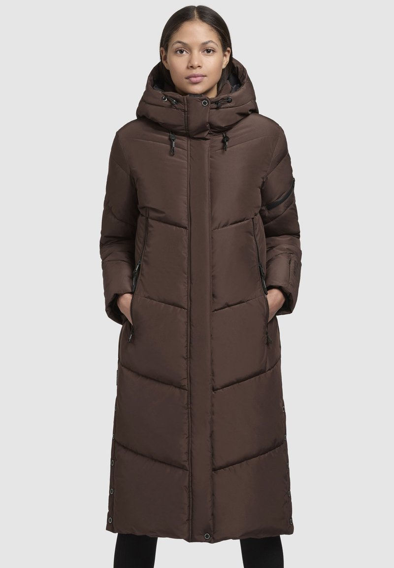 Geacă puf maro cu un design lung, guler înalt, glugă și buzunare cu fermoar. Prezintă modele quilted orizontale și verticale.