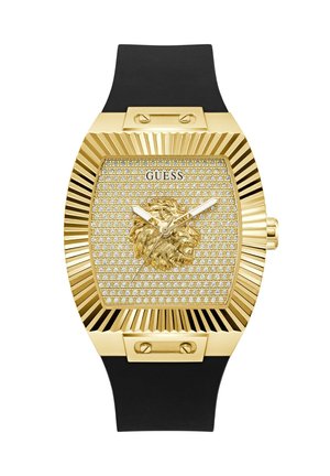 Reloj Guess en tono dorado con cabeza de león decorada en la esfera adornada con cristales, bisel rectangular con relieve y correa de silicona negra.