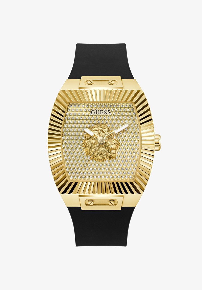 Montre Guess ton or avec tête de lion ornée sur un cadran incrusté de cristaux, lunette rectangulaire rainurée et bracelet en silicone noir.