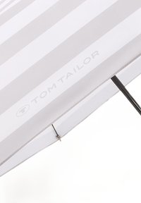 White umbrella with gray stripes, featuring a solid handle and metal ribs. "TOM TAILOR" branding visible on the canopy.