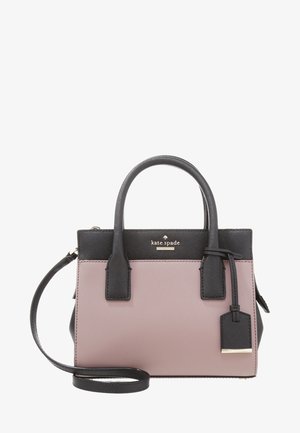 Pequeño bolso Kate Spade con asas negras, correa y borde superior sobre un cuerpo color malva, con una etiqueta colgante y un logo dorado.