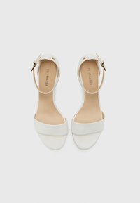 Hvite hæl sandaler med bred frontstropp, smal ankelrem og gullhardvare. Glatt kunstlær tekstur med et minimalistisk design.