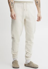 Crème-kleurige sweatpants van zachte stof met een taps toelopende pasvorm, elastische tailleband en ribgebreide manchetten. Voorzien van een trekkoord voor een verstelbare pasvorm.