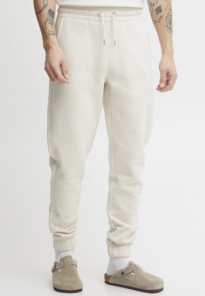 Crème-kleurige sweatpants van zachte stof met een taps toelopende pasvorm, elastische tailleband en ribgebreide manchetten. Voorzien van een trekkoord voor een verstelbare pasvorm.