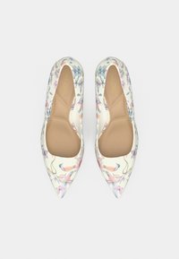 Talons hauts imprimés de fleurs avec une surface extérieure en cuir blanc, un bout pointu, une semelle intérieure beige et une texture lisse. Présente des motifs de fleurs roses et bleues.