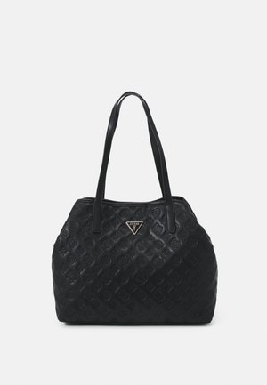 Black handbag with embossed floral pattern, two shoulder straps, and a metallic triangular Guess logo on the front center.
