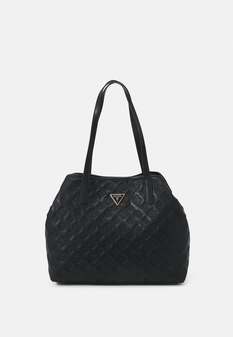 Sac à main noir avec motif floral en relief, deux anses pour l'épaule, et un logo triangulaire métallique Guess au centre avant.