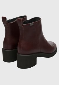 Burgundy leather ankle boots with a smooth finish, rounded toe, and sturdy black block heel. Features dual pull tabs for easy wear.