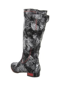 Knee-high boots in black and white abstract pattern with red stitching and hardware accents, featuring a small block heel and textured fabric.