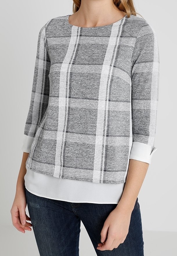 Pull à carreaux gris et blanc avec un col rond, des manches trois-quarts et un ourlet blanc uni, confectionné dans un tissu doux et texturé.