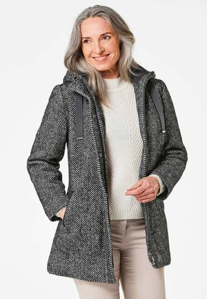 Grau gestreifter Mantel im Fischgratmuster mit Kapuze, grauen Akzenten und seitlichen Taschen, getragen über einem crèmefarbenen Strickpullover. Leichtes Material, Midilänge.