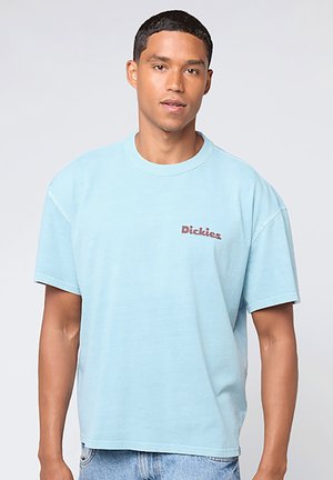 Camiseta de algodón azul claro con un corte relajado, cuello redondo y mangas cortas. Presenta un pequeño logo en rojo oscuro de "Dickies" en el pecho.