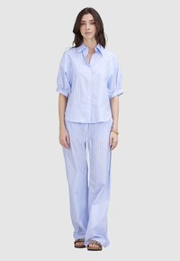 Hellblau gestreiftes Hemd mit kurzen Ärmeln, kombiniert mit passenden weit geschnittenen Hosen. Beide Teile haben eine glatte Textur und einen lockeren Sitz.