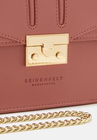 Rosa strukturiert Leder Umhängetasche mit einem goldenen Verschluss und Kettenriemen. Verfügt über das eingeprägte Markenlogo und Nahtdetails.