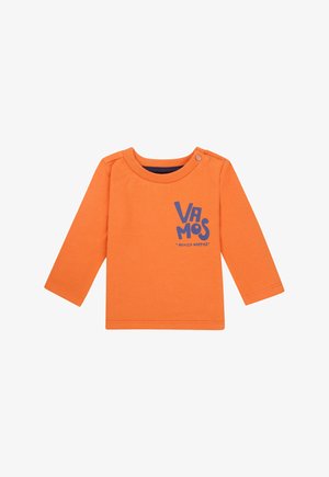 Langes orange Hemd aus Baumwolle mit navy Rundhalsausschnitt, das auf der Vorderseite den blauen Grafiktext "VA MOS" und einen Druckknopf an der Schulter hat.