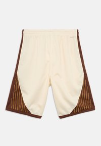 Krem kratke hlače s smeđim bočnim panelima koji imaju dijagonalne žute pruge. Izrađene od prozračnog materijala, imaju elastični pojas za udobnost.