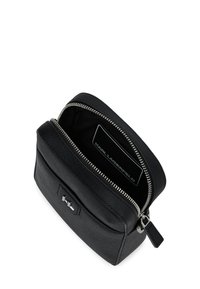 Pungă neagră texturată din piele, cu fermoar argintiu, buzunar frontal și logo "KL", deschisă pentru a arăta eticheta interioară "Karl Lagerfeld".