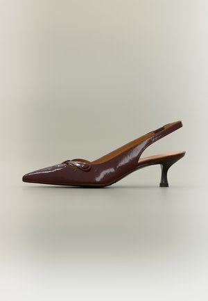 Décolleté slingback in vernice marrone scuro con punta appuntita, tacco kitten basso e piccola fibbia decorativa sulla tomaia.