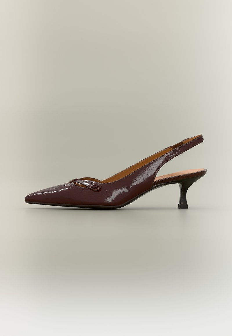 Escarpin slingback en cuir verni marron foncé avec bout pointu, petit talon kitten bas et petite boucle décorative sur le dessus.