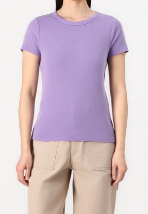 Fioletowy prążkowany t-shirt z krótkim rękawem, klasycznym okrągłym dekoltem, dopasowanym krojem i gładką fakturą, zestawiony z beżowymi szerokimi spodniami.