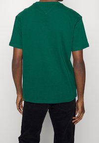 Grön crewneck t-shirt i bomull, med korta ärmar, en avslappnad passform och sömnadsdetaljer på kragen och fållen.