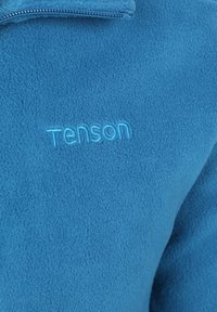 Blauwe fleecjas met een hoge kraag, voorzien van een rits en geborduurd "Tenson" logo in lichtblauw aan de voorkant. Zachte textuur.