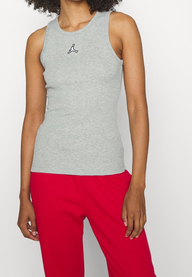 Gray sleeveless tank top with a round neckline and a small black logo on the chest, paired with red loose-fit pants.