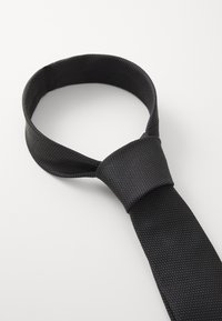 Melns tauriņš ar teksturētu audumu, kas izceļas ar smalku punktu rakstu. Tauriņš ir tradicionālā formā ar plašu galu un šauru galu.