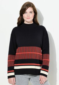 Schwarzer Strickpullover mit hohem Kragen, der horizontale rote und cremefarbene Streifen aufweist, sowie langen Ärmeln mit gestreiften Akzenten an den Bündchen.