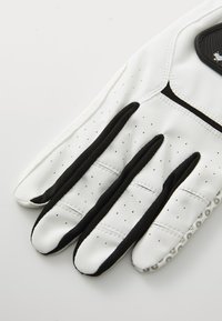 Luvas de golfe brancas com detalhes em preto, textura perforada, áreas de aderência flexíveis e palma acolchoada para conforto. Design com três dedos visível.