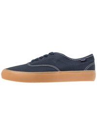 Sneakers in tela navy con cuciture bianche, design low-top, punta rotonda e suola in gomma marrone chiaro. Dettaglio di allacciatura con sei occhielli.