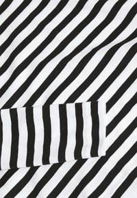 Schwarz-weiß gestrefter Stoff mit abwechselnd breiten und schmalen Streifen. Verfügt über einen abgerundeten Saum und eine glatte Textur.
