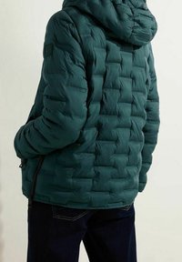 Tyrkysová prošívaná puffer bunda s kapucí, která má texturovaný povrch. Obsahuje zipové kapsy a žebrované detaily na manžetách.