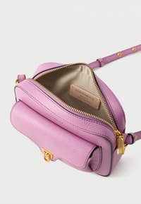 Pink leather crossbody bag with a textured finish, zip closure, gold hardware, and a beige lining. Features a logo tag inside. Adjustable strap.
