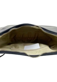 Černá kožená psaníčko s zlatým zipem. Interiér je béžová látka s malou bílou štítkem viditelným. Zipová uzávěrka nahoře.