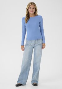 Lichtblauw, geribbeld T-shirt met lange mouwen, gecombineerd met brede, vervaagde denim jeans. Gladde textuur, casual pasvorm en eenvoudig design. Zwarte schoenen maken de look compleet.