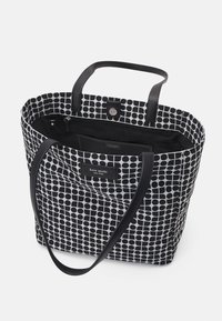 Borsa a spalla in tela bianca e nera con motivo a pois, dotata di doppi manici, chiusura magnetica e tasca interna con zip.