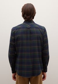 Vista trasera de una camisa de cuadros en azul oscuro y verde con acentos naranjas, con mangas largas y puños con botones, hecha de tela suave.