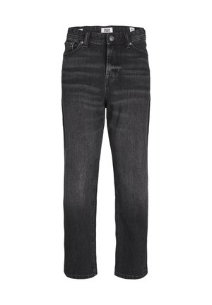 Enfant portant un t-shirt jaune moutarde Jack & Jones, un jean noir ample et des baskets blanches avec des accents bleus, debout sur un fond gris.